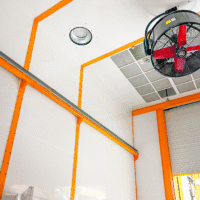 Ceiling-mounted ventilation system with exhaust fan and filtration panels inside an industrial paint wash room
